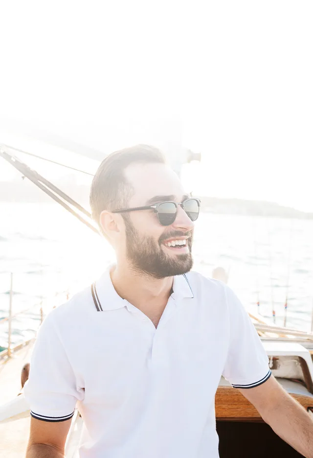 A smiling patient in sunglasses on a boat